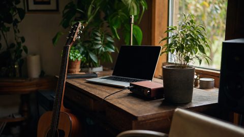 A producer reviewing music files and documentation on a laptop, representing AI provenance and policy compliance