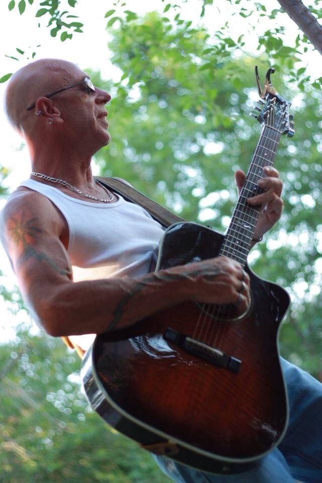 Brian Curry playing an acoustic guitar outdoors