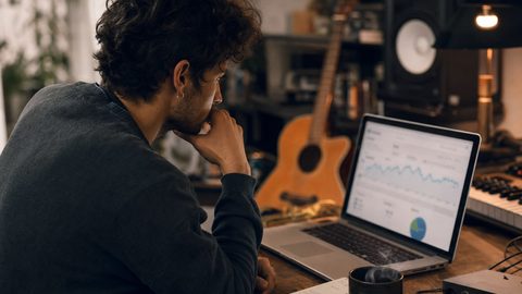 An independent artist reviewing Spotify for Artists dashboard data on a laptop